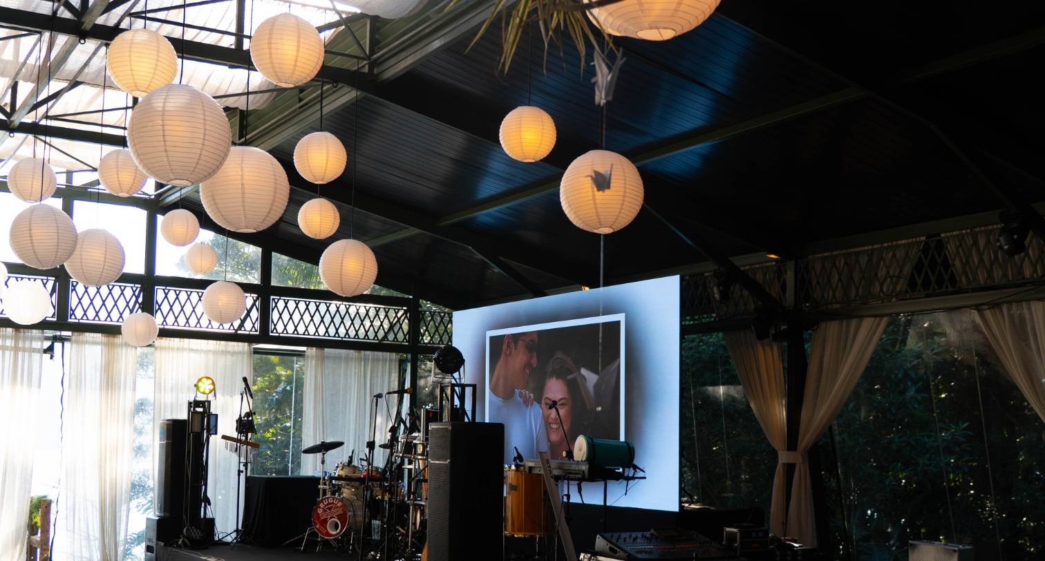 Estação de doces com painel floral iluminado em um evento premium em São Paulo